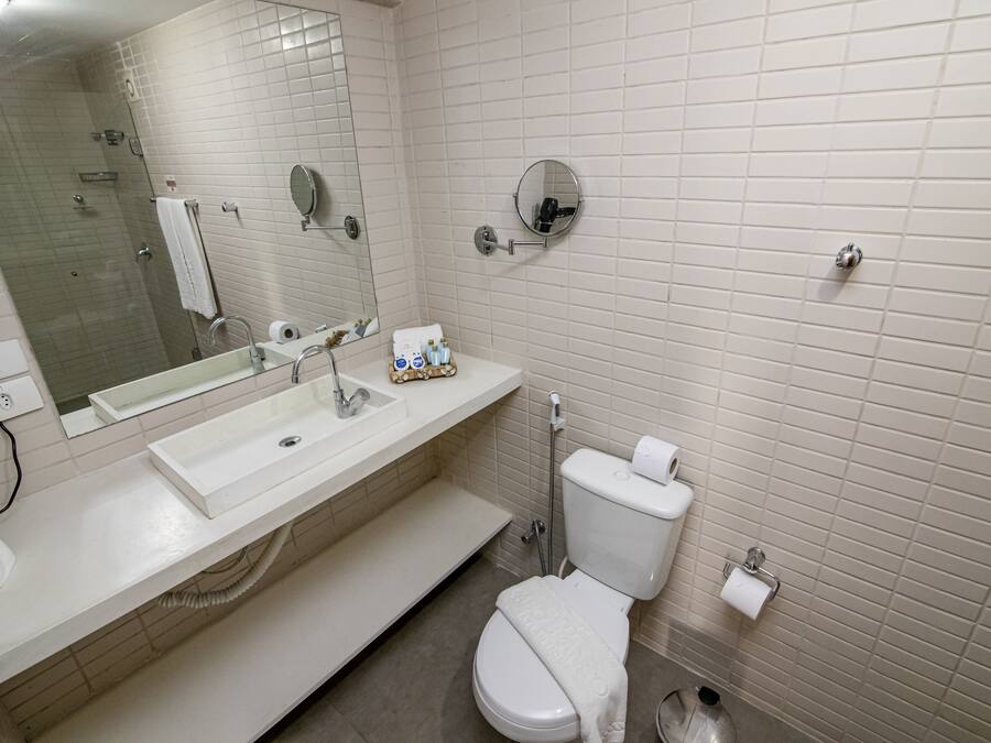 A modern bathroom with a white sink, mirror, and toilet.