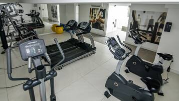 A gym with treadmills, elliptical machines, and exercise balls.