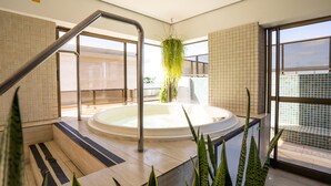 A modern indoor pool area with a hot tub, clear glass doors, and potted plants. - Hotel Cabo Branco Atlântico (João Pessoa)
