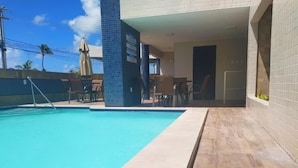 Una piscina al aire libre, sillones reclinables de piscina