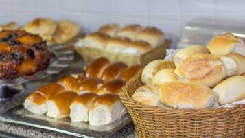 A buffet with various baked goods including rolls, bread, and pastries.
