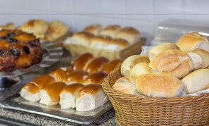 En buffet med forskellige bagværk, herunder rundstykker, brød og kager.