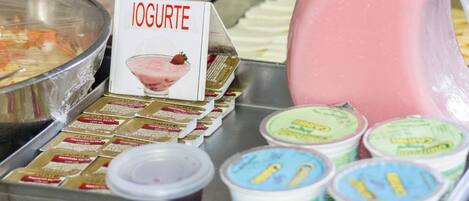 Una barra de yogurt con varios recipientes y una jarra de yogurt rosado.