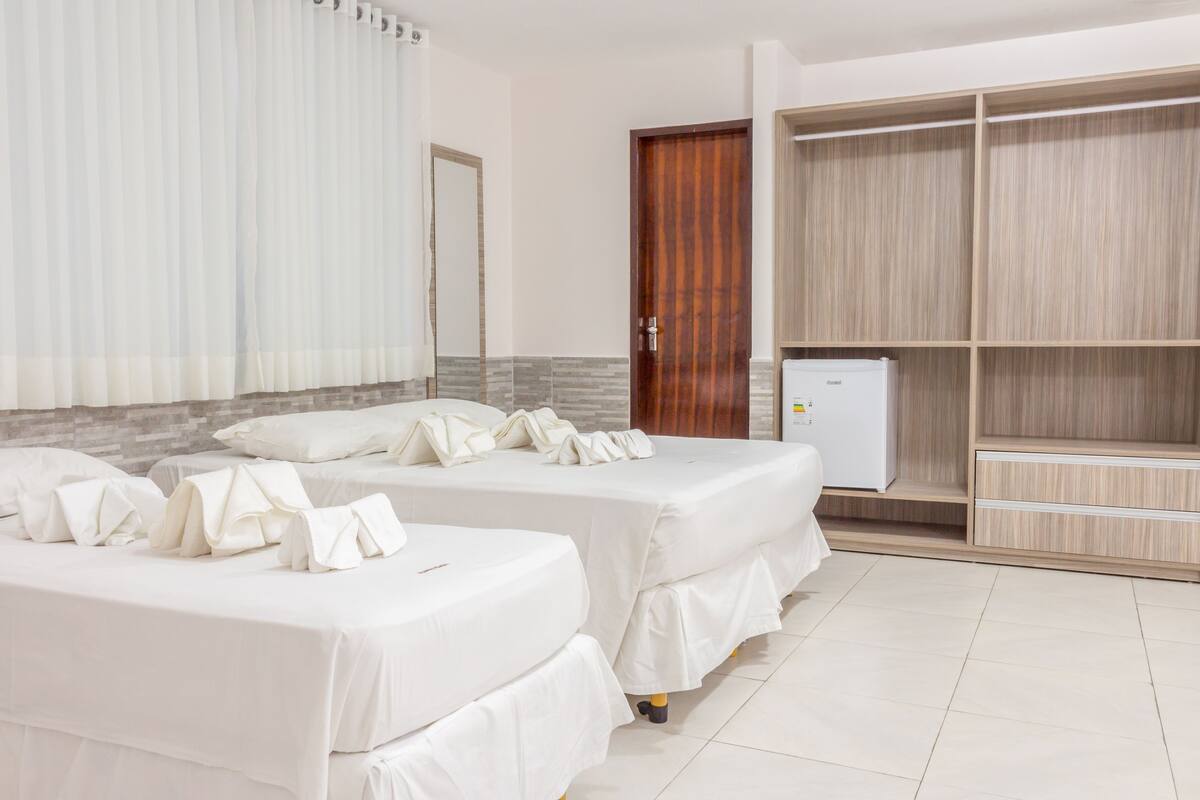 A hotel room with two beds, a wardrobe, and a minibar.