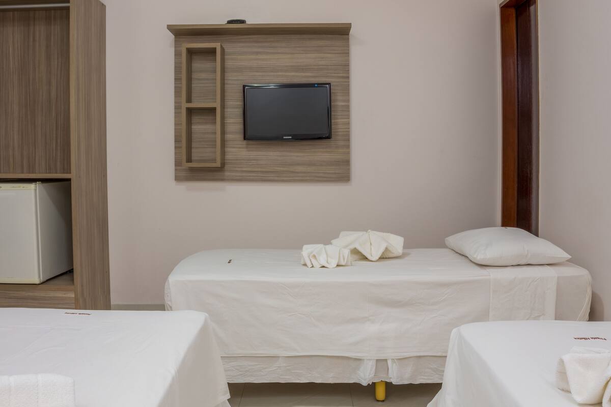 A hotel room with two beds, a television mounted on the wall, and a wardrobe.