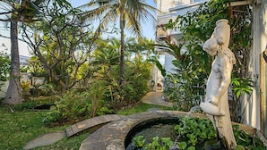 A garden with a statue, a pond with water lilies, and tropical plants. - Hotel Villa Morgane (Saint-Pierre)