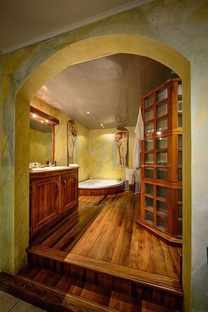 A bathroom with a wooden vanity, a bathtub, and a glass-enclosed cabinet.