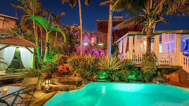 A nighttime pool area with a clear view of the pool, surrounding vegetation, and a small gazebo. - Hotel Villa Morgane (Saint-Pierre)