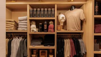 Un placard bien organisé, avec des vêtements soigneusement pliés, une variété de chapeaux et un mannequin portant un t-shirt d’hôtel.