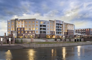 Un hotel de varios pisos con un diseño arquitectónico moderno, con balcones y vista al agua.