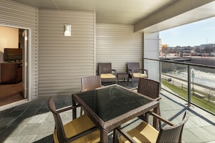 Un balcón con mesa y sillas, un televisor y vistas a un paisaje urbano.