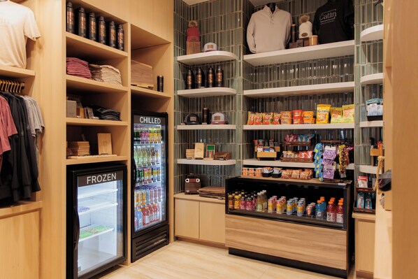 A retail space with shelves stocked with various products, a refrigerated display, and a clothing rack. - Hilton Garden Inn Sioux Falls Downtown (Sioux Falls)