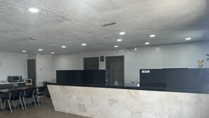 A modern kitchen with a marble countertop, a herringbone wood floor, and recessed ceiling lighting. - Motel 6 New Boston, TX (New Boston)
