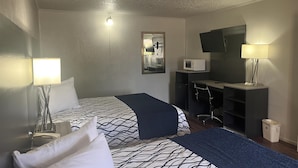 A hotel room with two beds, a desk, a chair, a microwave, a TV, and a trash bin. - Motel 6 New Boston, TX (New Boston)