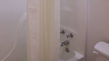 A bathroom with a bathtub, toilet, and shower curtain.