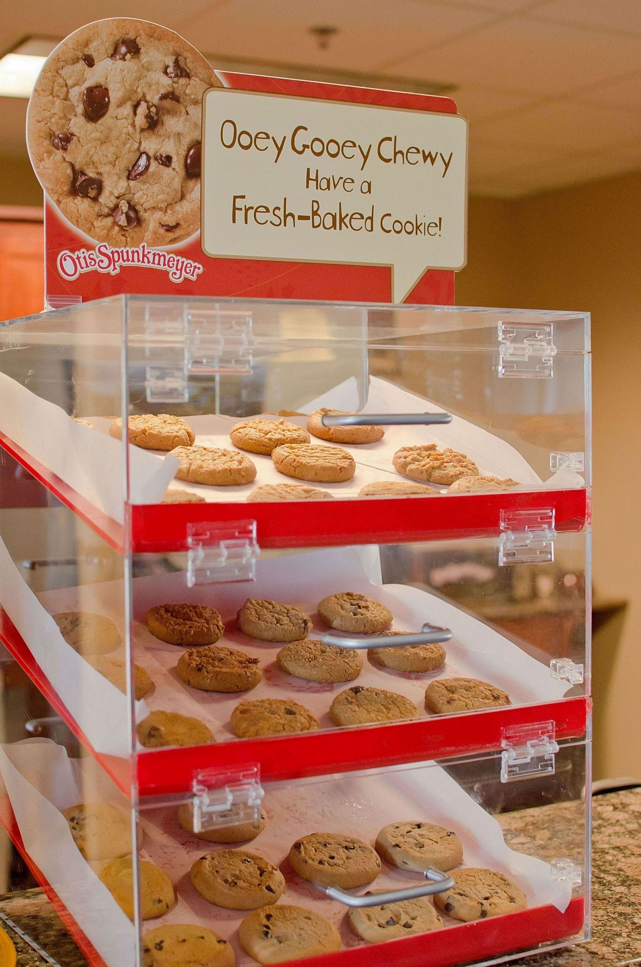 A bakery display with various cookies and a sign advertising fresh-baked cookies.