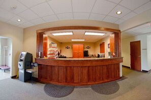 A reception area with a wooden counter, a cash register, and a vending machine.