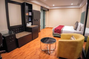 Habitación de hotel con escritorio, silla, cama y un sillón amarillo.