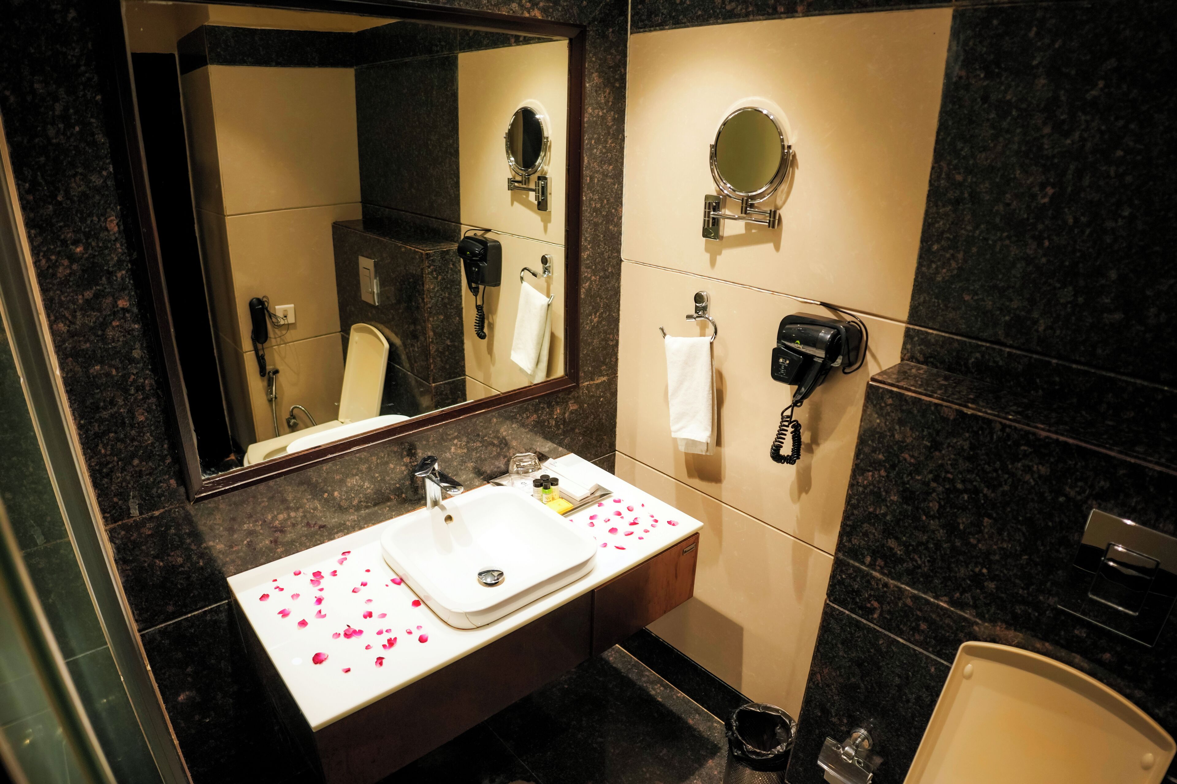 A bathroom with a sink, mirror, hairdryer, and towel rack.