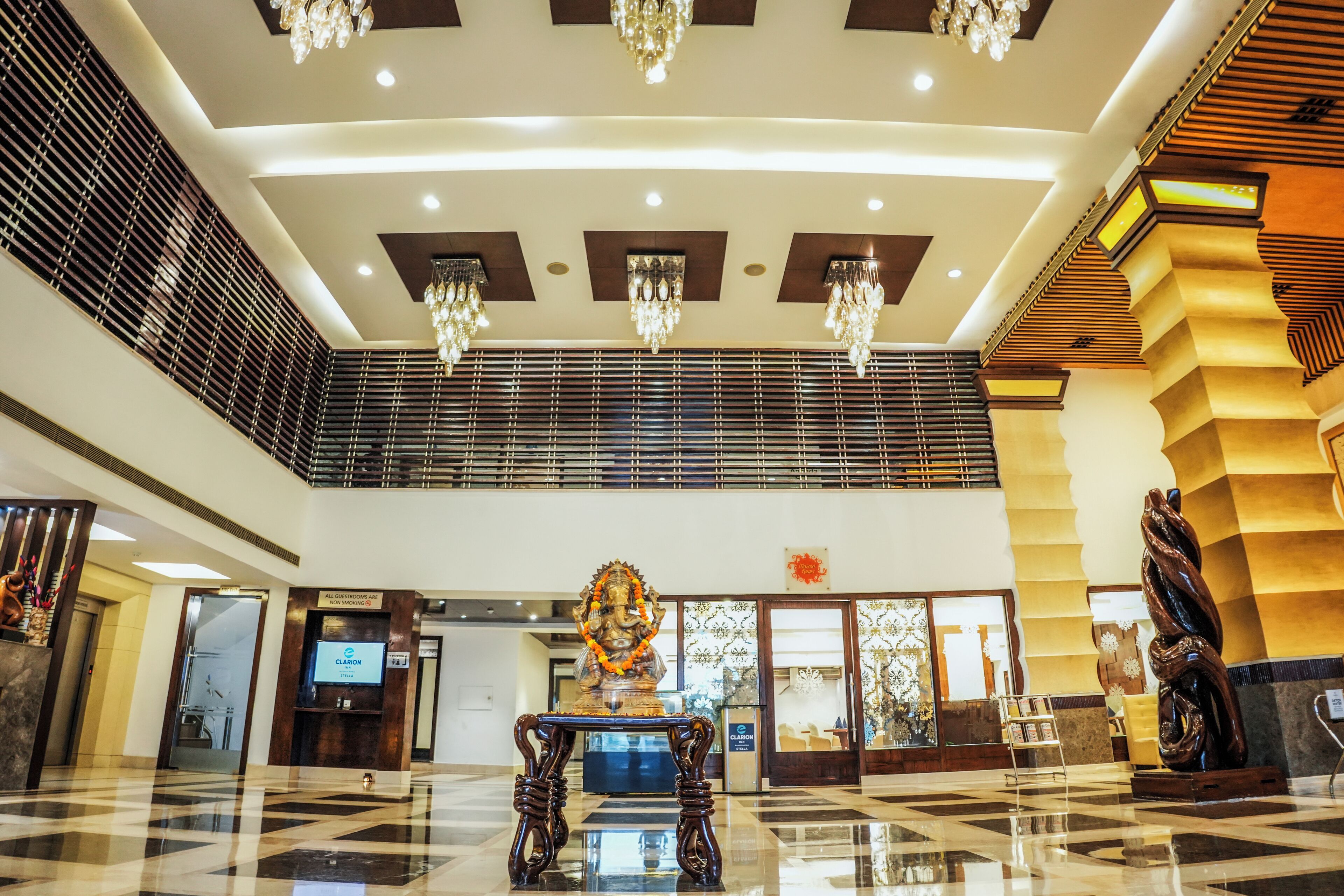 Eine Hotelhalle mit Schachbrettfußboden, Kronleuchtern, einer Statue und einer Treppe.