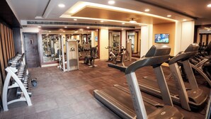 A gym with treadmills, weight machines, and a mirror wall. - Clarion Inn Stella (Bathinda)