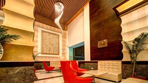 A lobby with red chairs, a wooden ceiling, and a large wall mural. - Clarion Inn Stella (Bathinda)