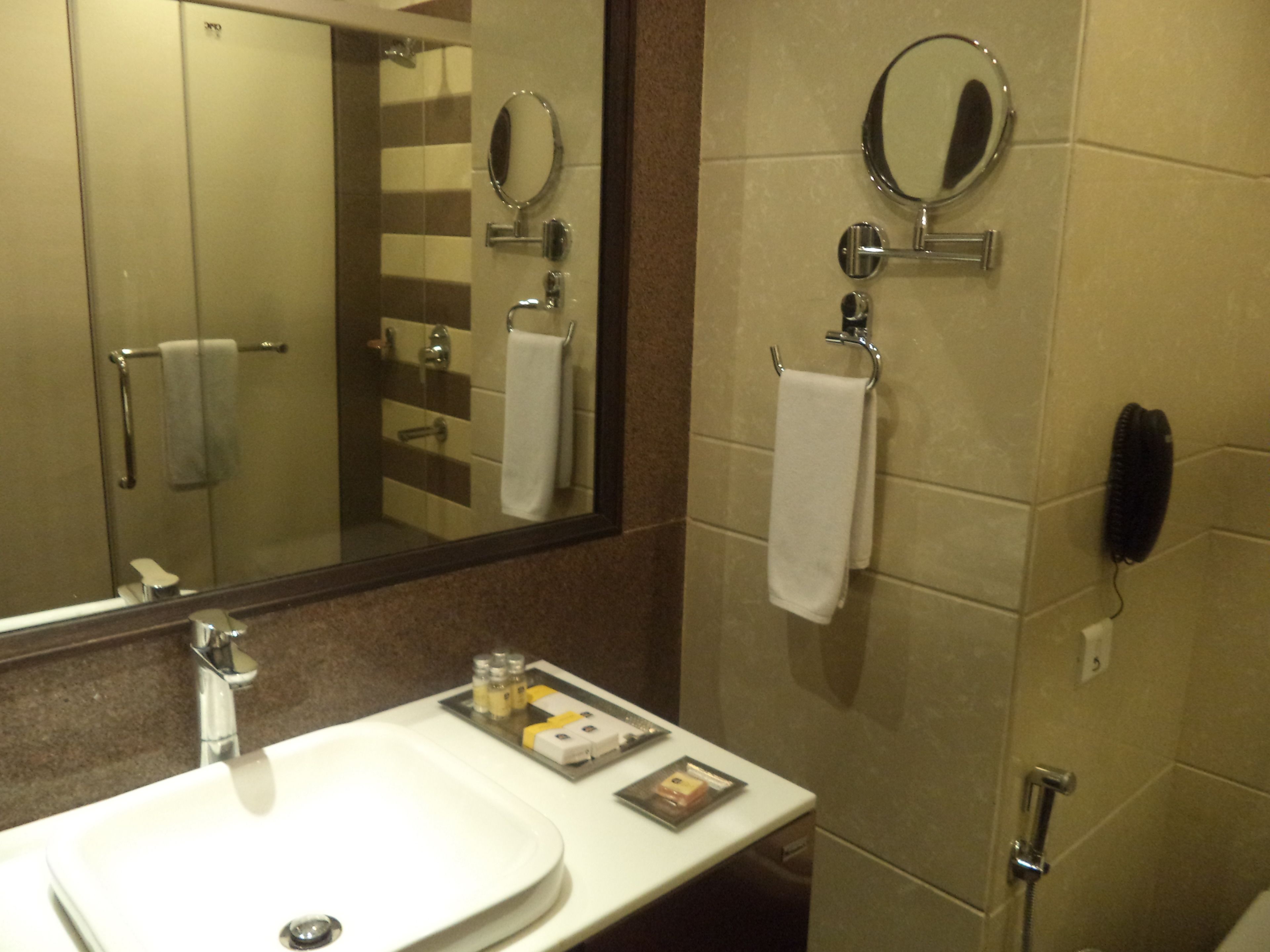 A bathroom with a sink, mirror, towel rack, and a telephone.