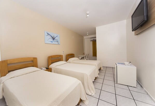 Habitación de hotel con dos camas, televisión montada en la pared, una mesita y una lavadora.