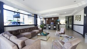 Rebedor d'hotel amb taulell de recepció, un sofà, butaques i una taula de cafè.
