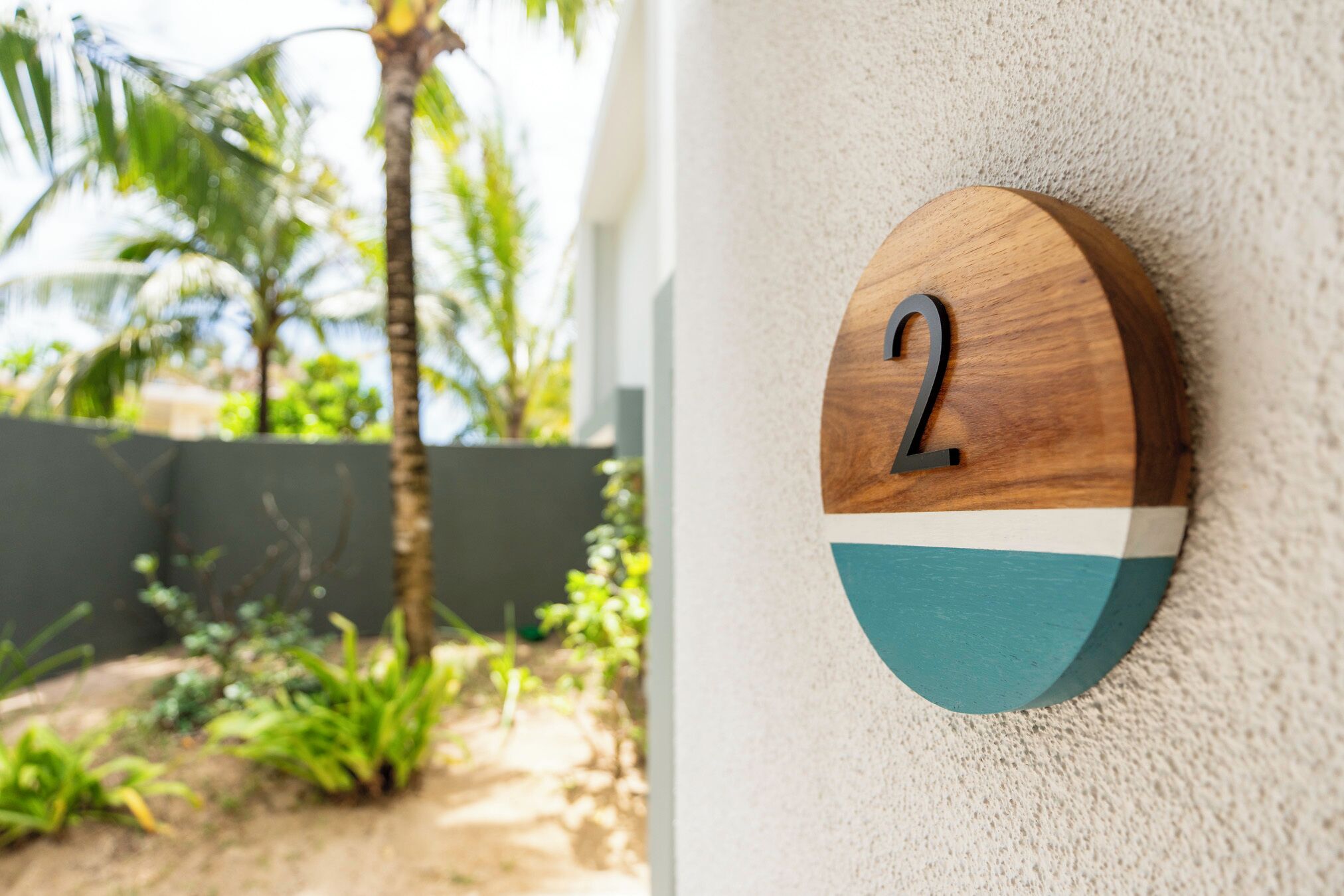 A wooden number plaque with the number 2 on a textured wall.