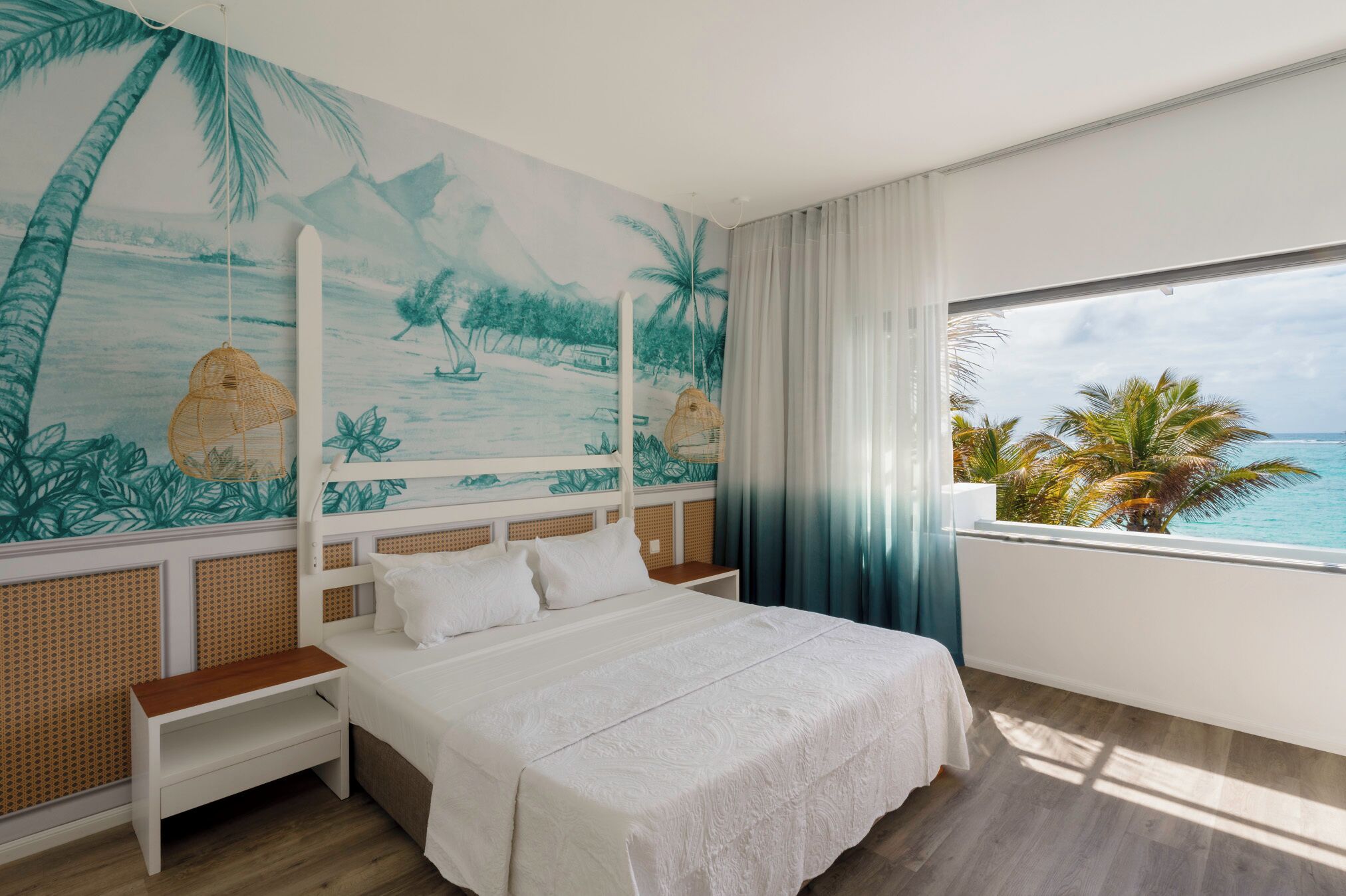 A bedroom with a large bed, a view of the ocean, and a mural of a beach scene.