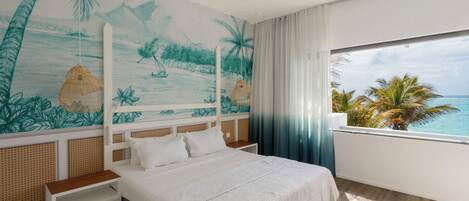 A bedroom with a large bed, a view of the ocean, and a mural of a beach scene.
