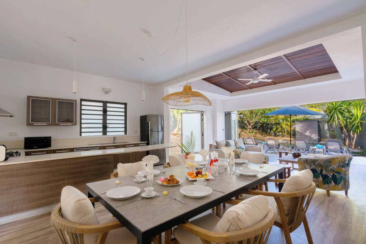 Una cocina moderna con comedor, ventanas amplias y vistas al exterior.