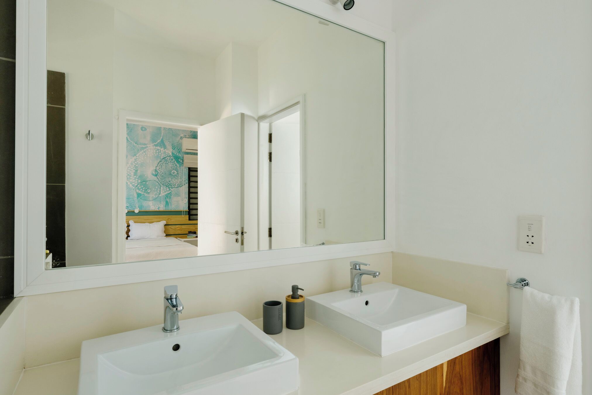 A modern bathroom with two white sinks, a large mirror, and a wooden vanity.