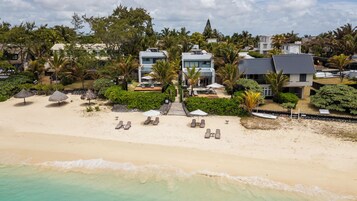 Una propiedad frente a la playa con varias villas, una playa de arena y palmeras.