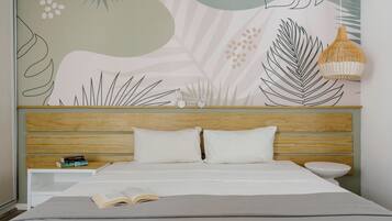 Un dormitorio con una cama, una mesita de noche con libros, una lámpara colgante y una pared con diseño de hojas.