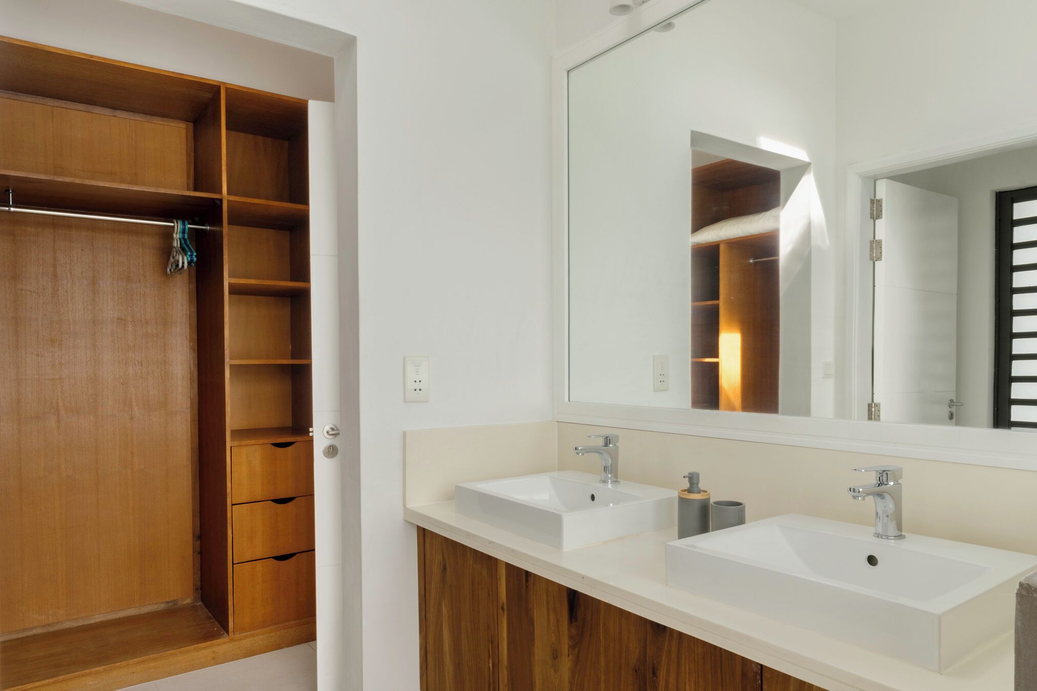 Een moderne badkamer met twee wastafels, een grote spiegel en een houten wastafelmeubel.