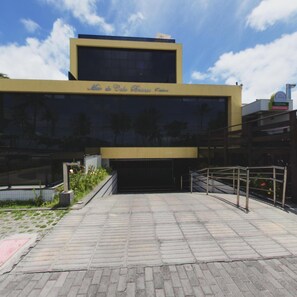 Un edificio moderno con un amplio muro de vidrio y un letrero sobre la entrada que dice 'Man do Cabaça Evê'.