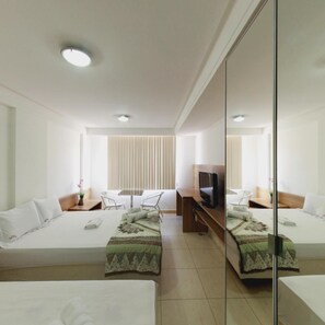 Habitación de hotel con dos camas, televisión, escritorio y espejo.