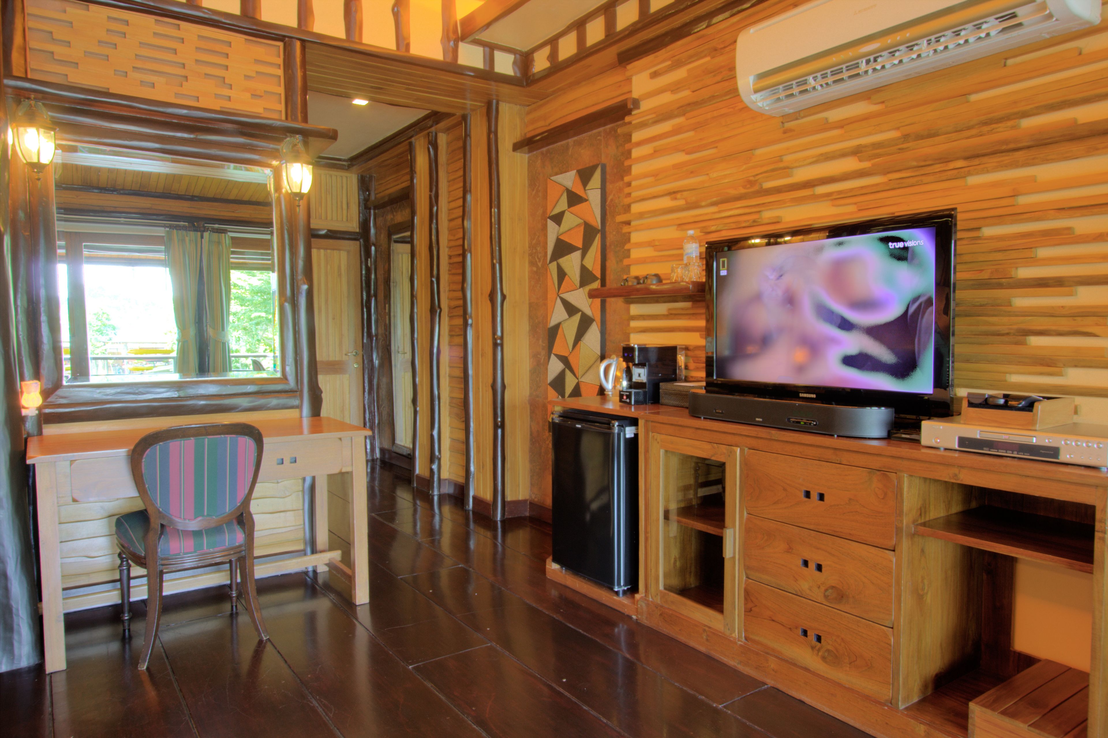 A compact kitchen with a built-in refrigerator, a coffee maker, and a flat-screen TV on a wooden countertop.