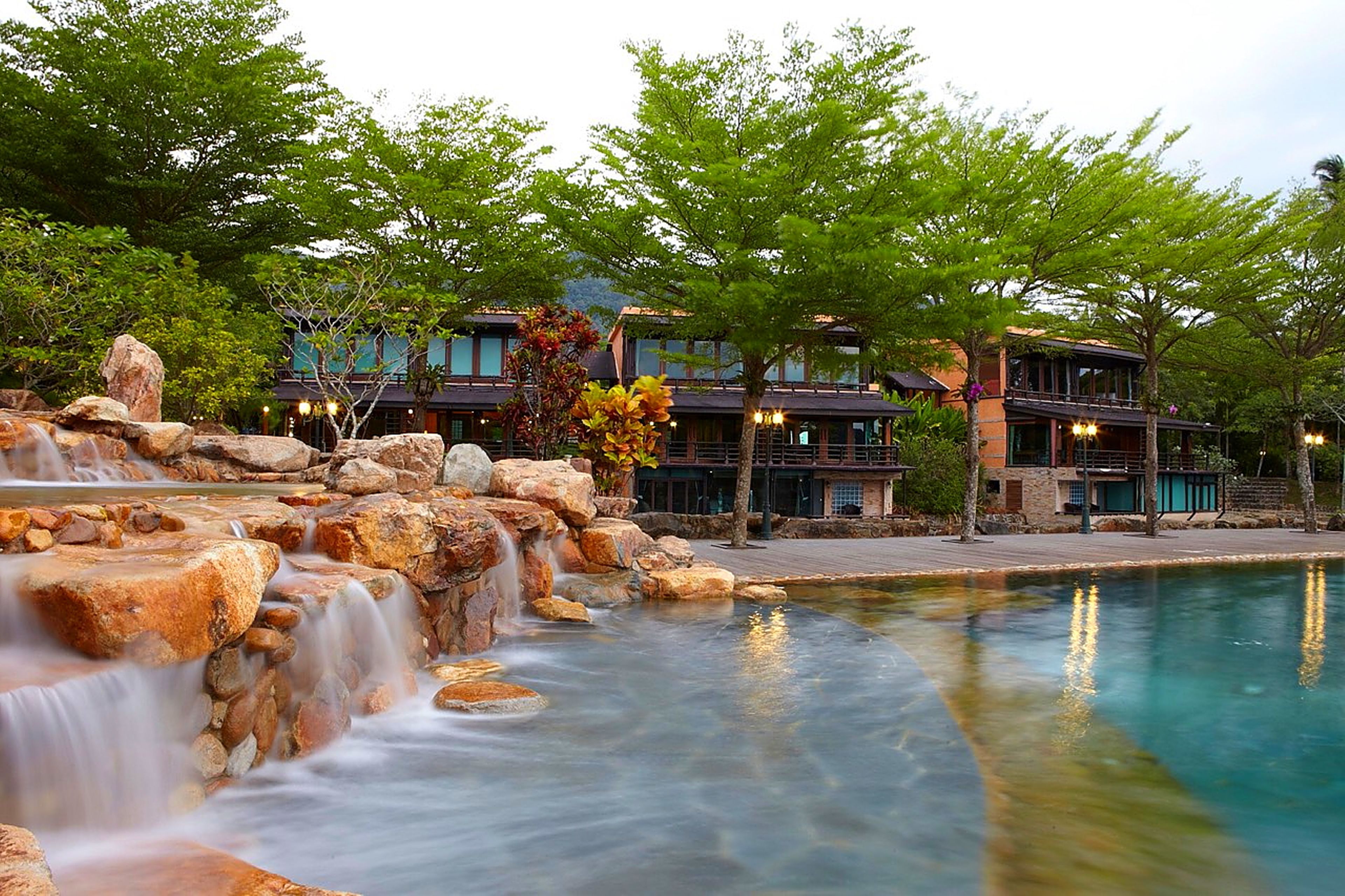 A hotel with a waterfall, pool, and traditional architecture.