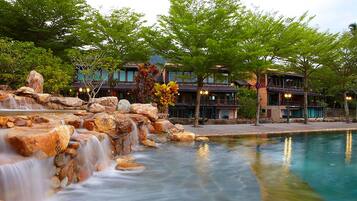 A hotel with a waterfall, pool, and traditional architecture.