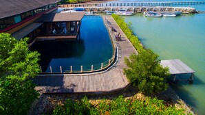 Een resort met een zwembad, een houten terras en boten.