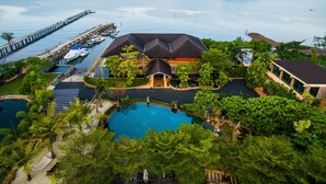 Un resort con piscina, un muelle con barcos y vistas a una gran masa de agua y una isla distante.