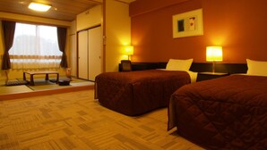 A hotel room with two beds, a small table, and a sofa. - KUROHIME KOGEN HOTEL (Shinano)