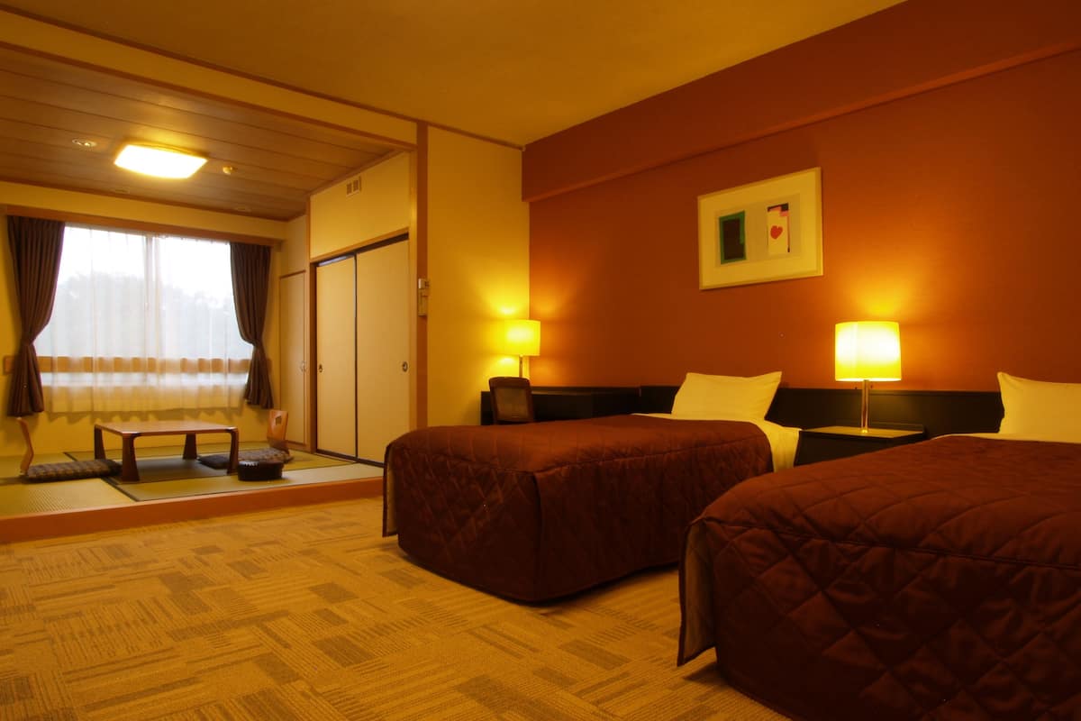 Una habitación de hotel con dos camas, una mesita pequeña y un sofá.