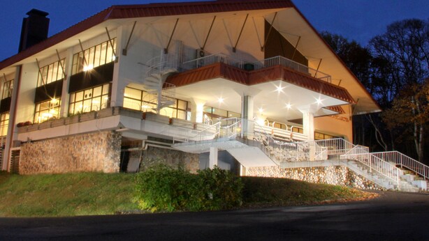 A modern building with a stone facade, multiple balconies, and a staircase leading to the upper level. - KUROHIME KOGEN HOTEL (Shinano)