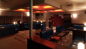 A dimly lit lounge area with checkered flooring, blue seating, and a red accent wall. - KUROHIME KOGEN HOTEL (Shinano)