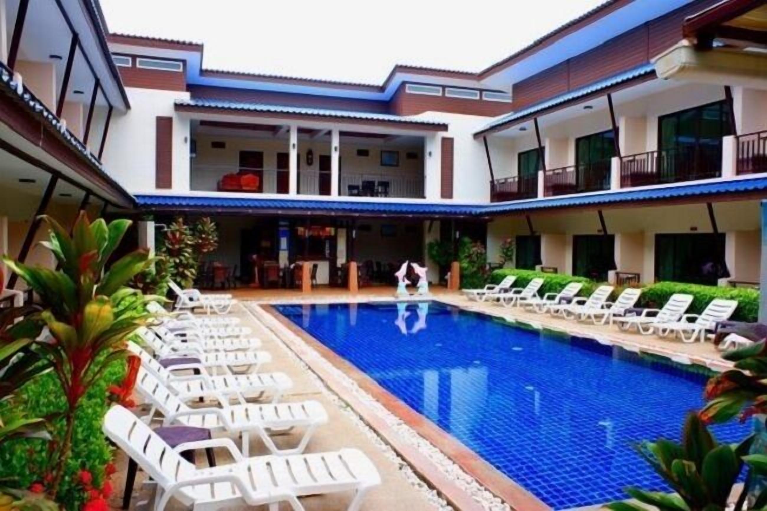 Une piscine avec des chaises longues et un bâtiment doté de balcons.