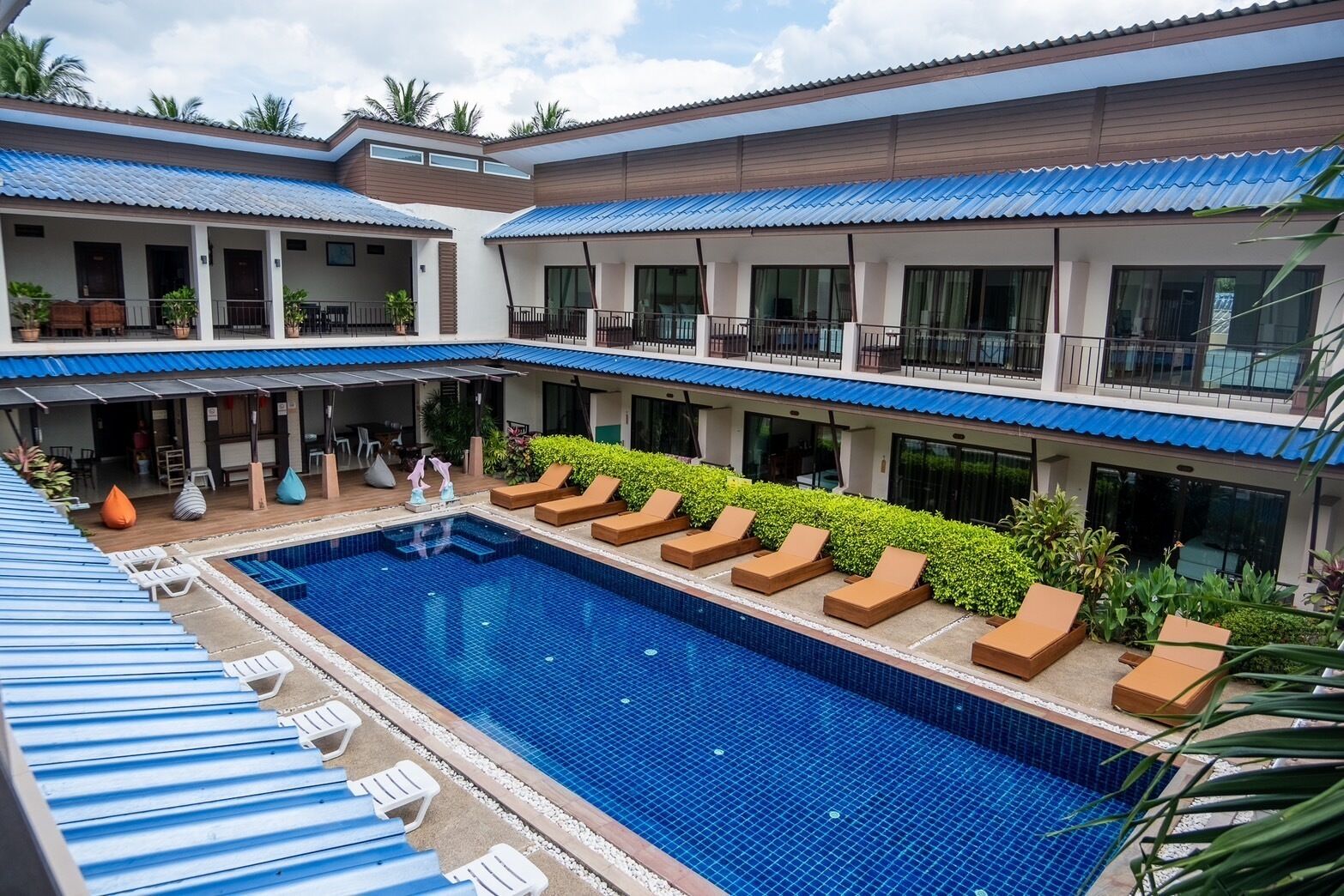A hotel with a central swimming pool, multiple balconies, and outdoor seating areas.